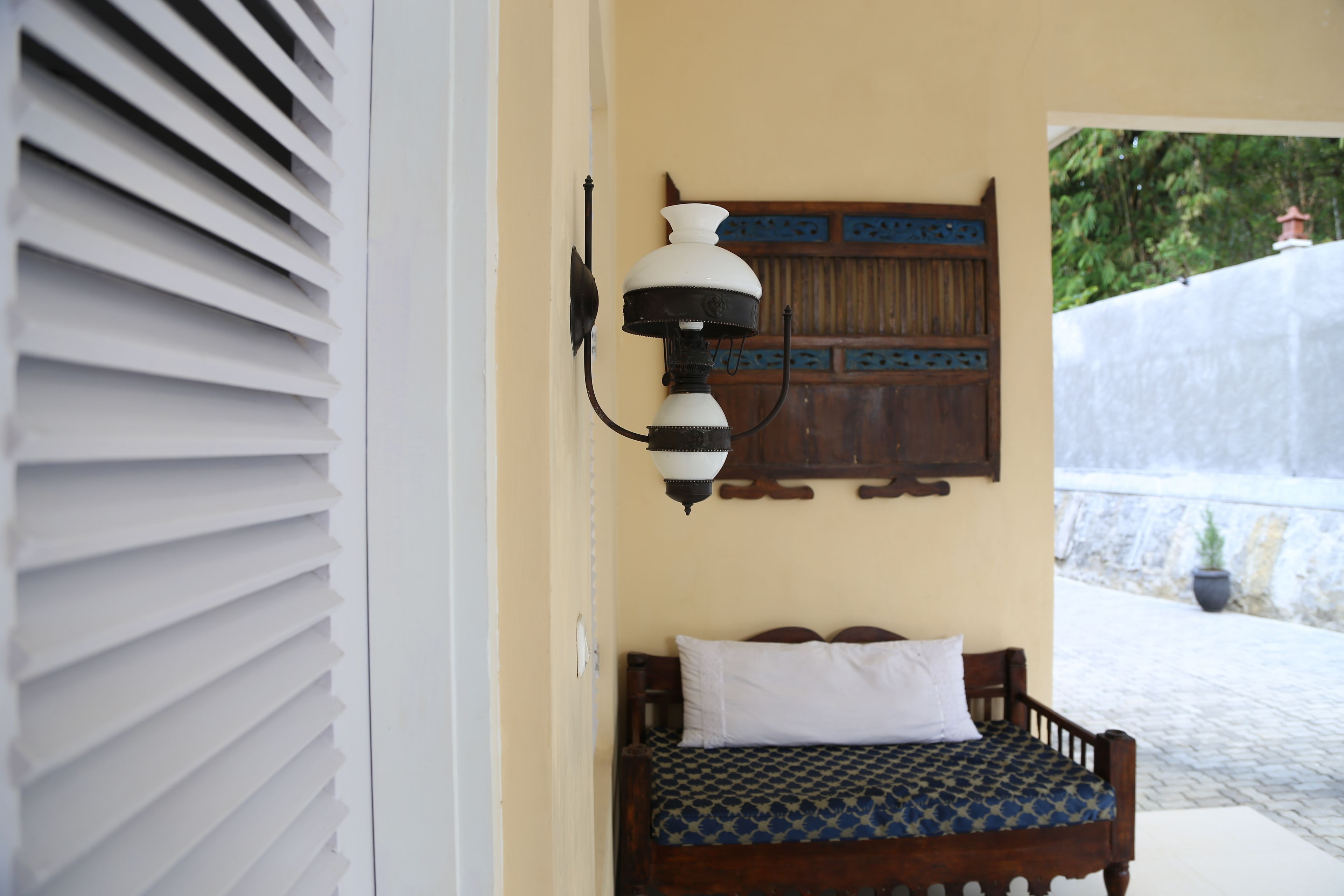 Un dormitorio con una cama, una lámpara de pared y una puerta de madera con un panel decorativo.