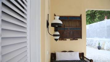 Un dormitorio con una cama, una lámpara de pared y una puerta de madera con un panel decorativo.