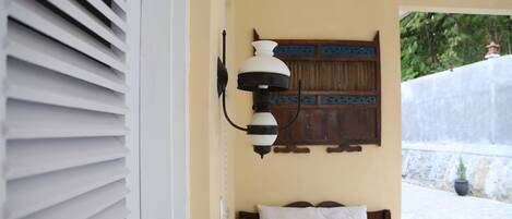 Un dormitorio con una cama, una lámpara de pared y una puerta de madera con un panel decorativo.