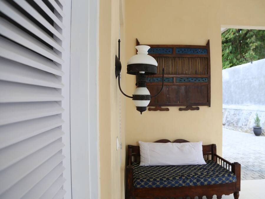 Un dormitorio con una cama, una lámpara de pared y una puerta de madera con un panel decorativo.