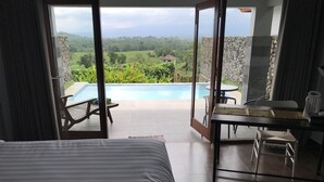 Un dormitorio con una cama grande, vista a una piscina exterior y un comedor con mesa y sillas.