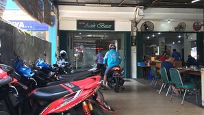 A motorcycle parked in front of a restaurant with a sign reading "Aesh Basar". - Hotel Aceh Besar (Jakarta)