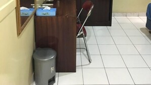 A room with a wooden desk, a chair, a trash bin, a mirror, and a wardrobe. - Hotel Aceh Besar (Jakarta)