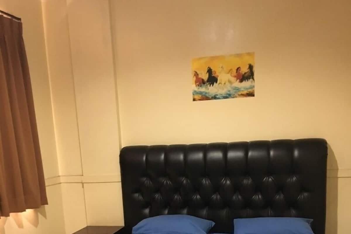 Un dormitorio con cabecera tapizada de color negro, dos almohadas azules y una colcha azul.