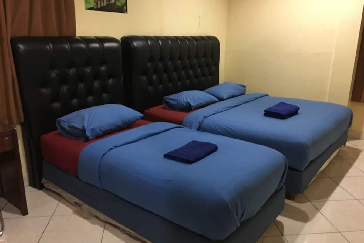 Habitación con dos camas, cada una con ropa de cama azul y colchón rojo.