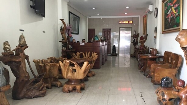 A lobby with a long reception desk, wooden sculptures, and a television mounted on the wall. - Hotel Aceh Besar (Jakarta)