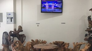 A room with a round wooden table surrounded by unique wooden chairs, a television mounted on the wall, and a 'No Smoking' sign. - Hotel Aceh Besar (Jakarta)