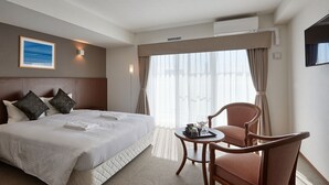 A hotel room with a large bed, a wooden headboard, a small round table with a tray of items, a chair, and a large window with curtains. - Creass Hotel TSUBOGAWA Marche (Naha)