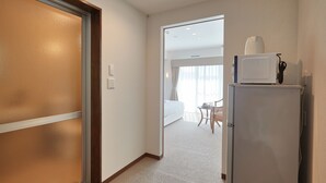 A hotel room with a bed, a small table with a chair, a microwave, and a refrigerator. - Creass Hotel TSUBOGAWA Marche (Naha)