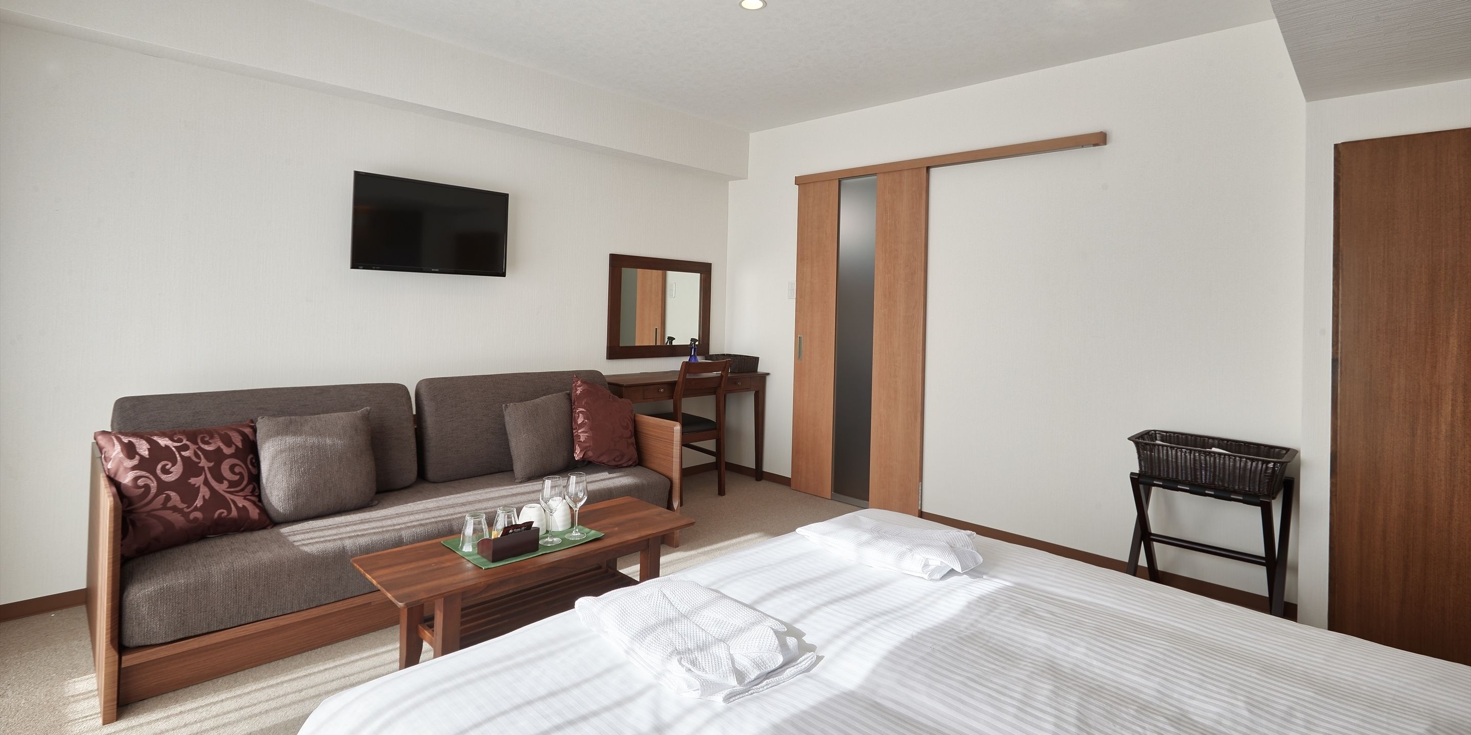 A hotel room with a bed, a sofa, a desk, a TV, and a wardrobe.