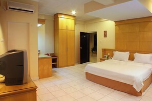 A hotel room with a bed, a desk, a wardrobe, and a television. - Hotel Hangtuah (Padang)