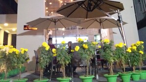 A building with a sign reading "Hotel Nirvana." There are outdoor umbrellas and potted plants in front. - Maya Heritage (Gaya)