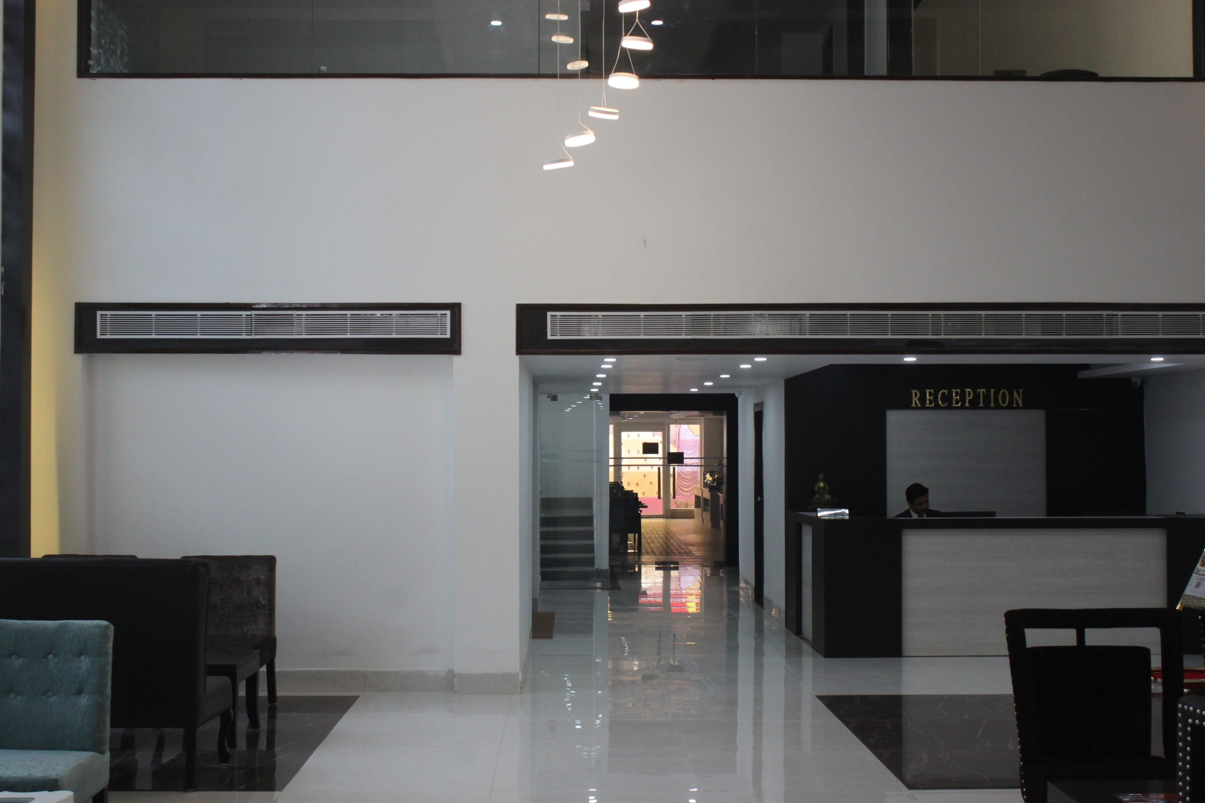 Zona de recepción con mostrador, área de asientos y una escalera que conduce a un nivel superior.