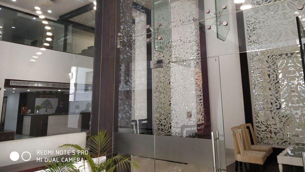 A reception area with a glass partition, a reception desk, and a chair. - Maya Heritage (Gaya)