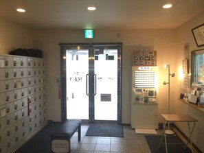 Un hall d’entrée comprenant un comptoir de réception, un banc, un classeur et un panneau d’affichage fixé au mur.
