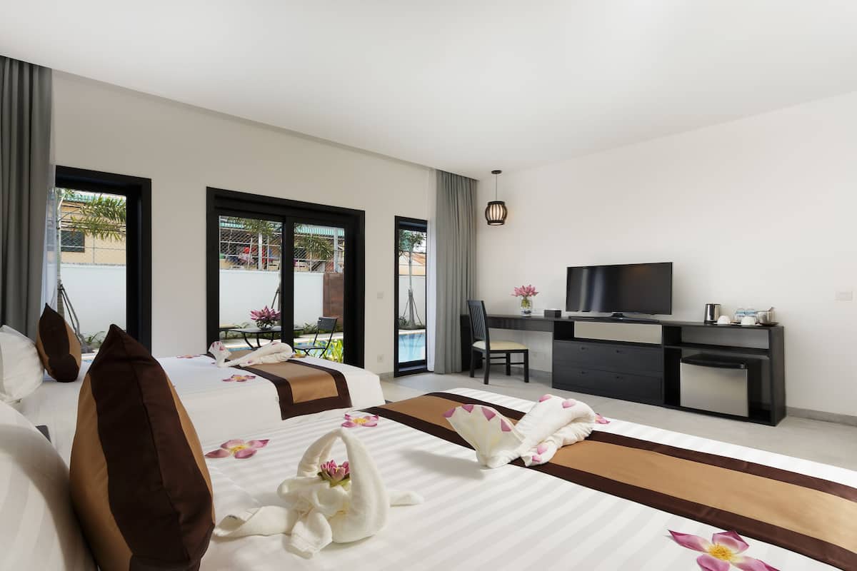 Ein modernes Hotelzimmer mit zwei Betten, einem Schreibtisch, einem Fernseher und Blick auf einen Swimmingpool.
