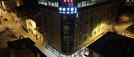 A hotel named "HOTEL AKDAĞ" with a modern design, featuring a prominent sign with three stars and a red roof.