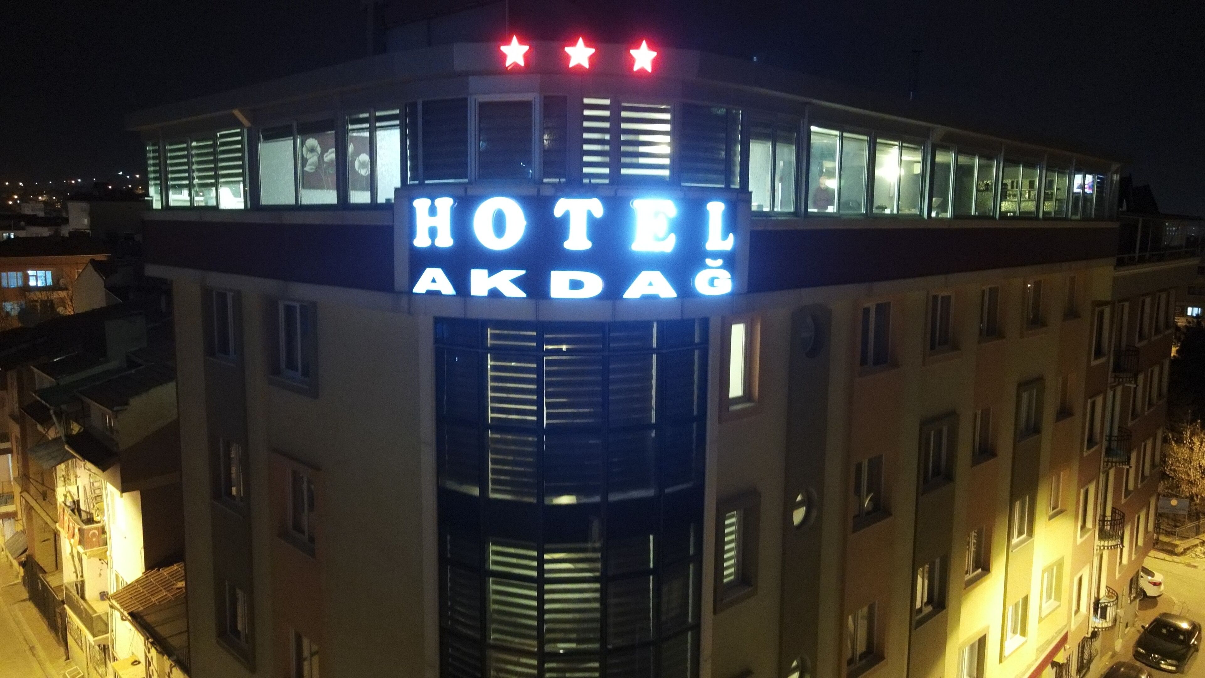 A hotel building with a prominent illuminated sign reading "HOTEL AKDAĞ" at the top.