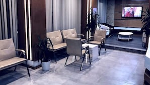 A modern lobby with leather sofas, a coffee table, and a TV mounted on the wall. - Hotel Akdag (Usak)