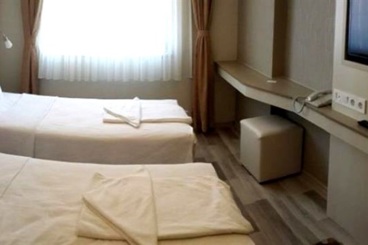 A hotel room with two beds, a TV, and a desk.