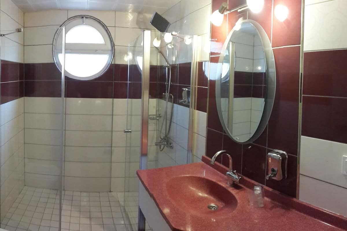 A bathroom with a glass-enclosed shower, a sink with a mirror, and tiled walls.