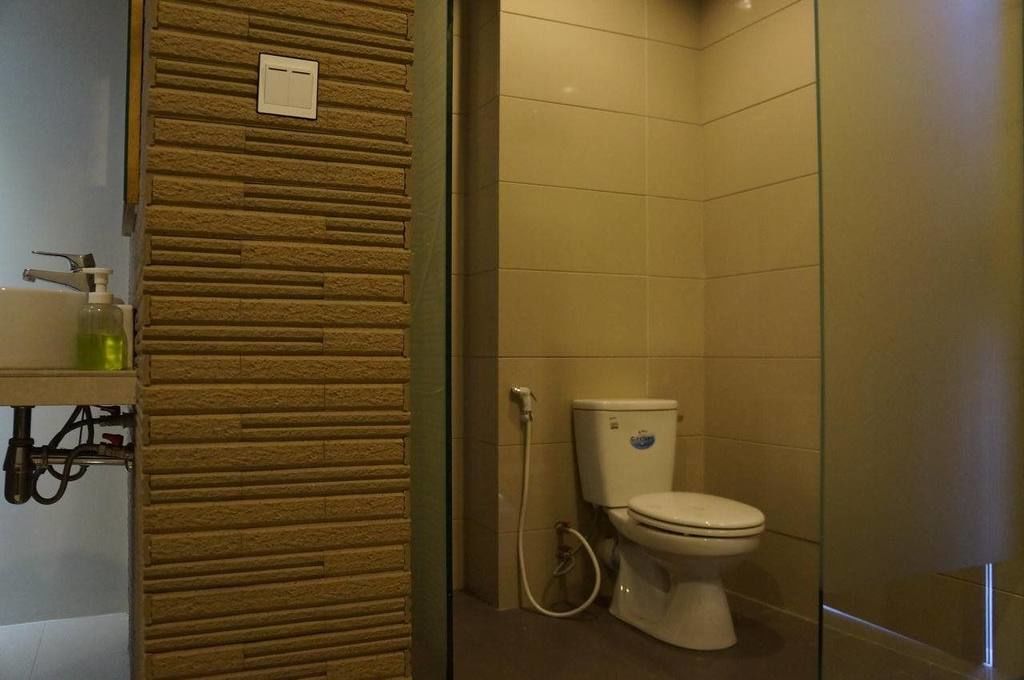 A bathroom with a toilet, a hand soap dispenser, and a shower area.