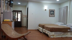 A room with a bed, a chair, a television, and a door. - Highland Lodge Hotel (Yangon)