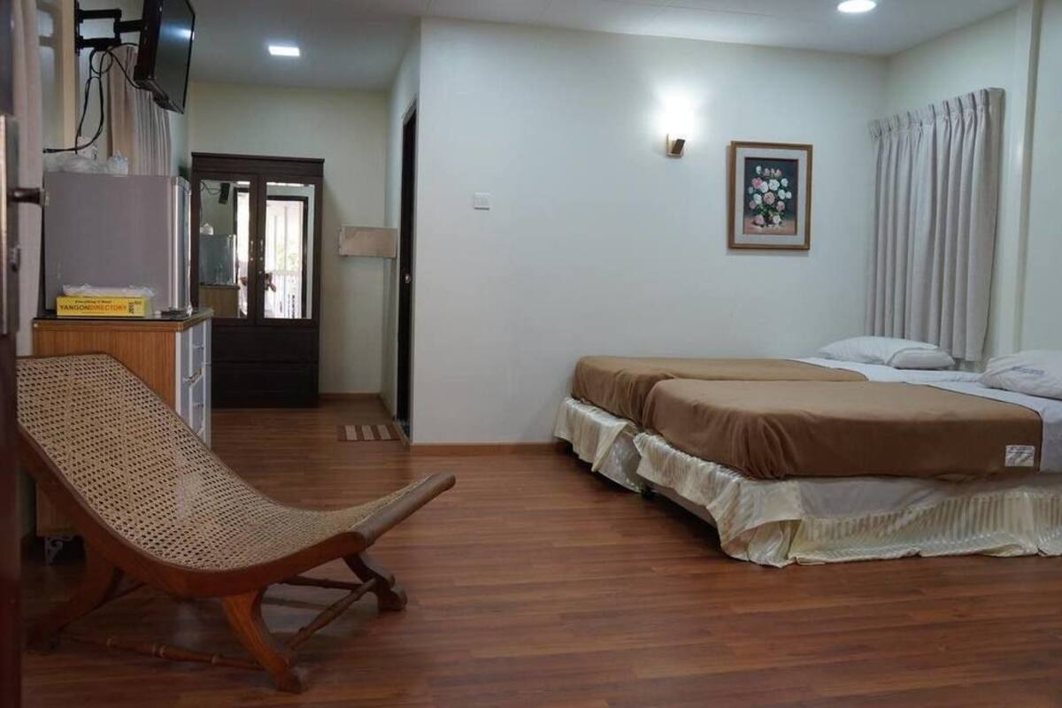A room with a bed, a chair, a television, and a door.