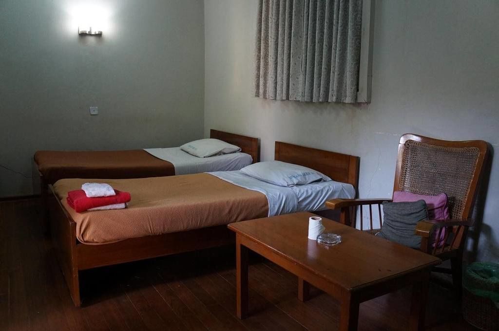 A room with two single beds, a wooden table, and a chair.