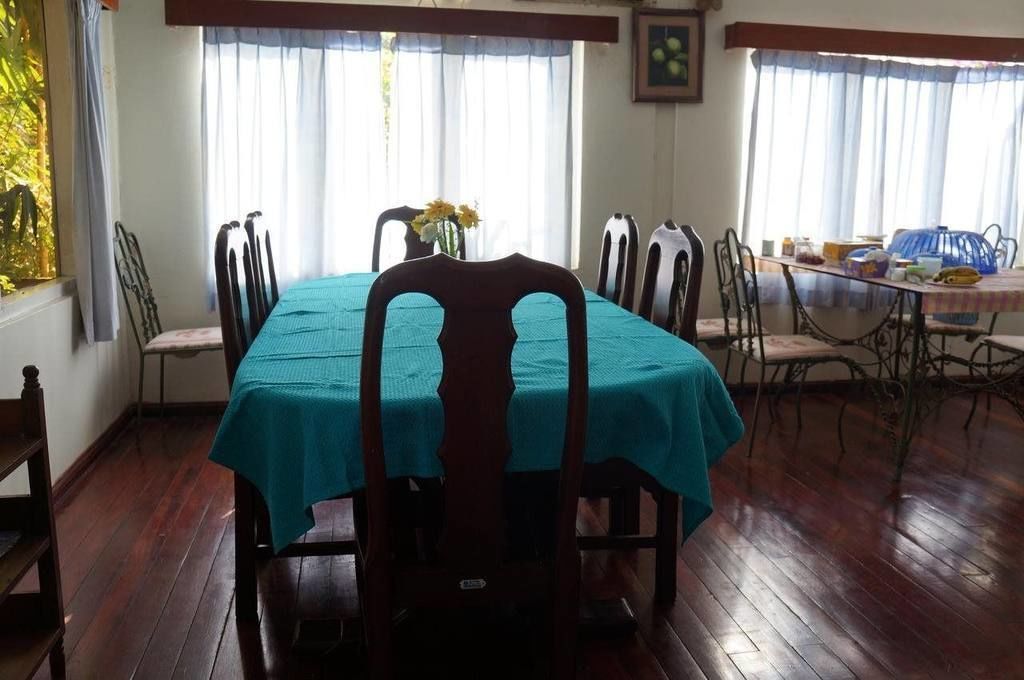 A dining area with a table covered by a teal tablecloth, surrounded by wooden chairs.
