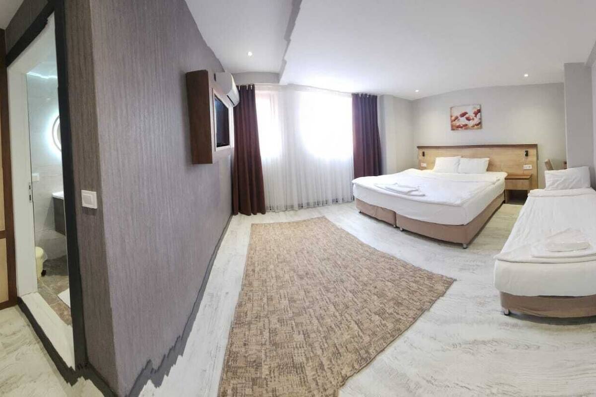 Una habitación de hotel con una cama grande, una cama más pequeña, un armario y un espejo.