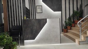 A modern reception area with a geometric design, a staircase, and potted plants. - Akdag Konaklama (Usak)