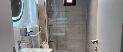 A modern bathroom with a large mirror, a sink, a toilet, and a shower area.