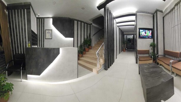 A modern lobby with a curved reception desk, a staircase, a seating area with cushioned benches, and a television screen. - Akdag Konaklama (Usak)