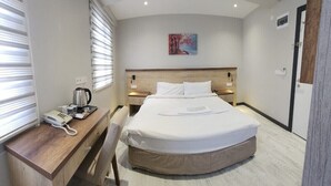 A hotel room with a bed, bedside table, and a desk with a telephone. - Akdag Konaklama (Usak)