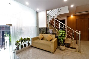 Relax in this inviting space with a sofa, potted plant, and staircase leading to an upper level.