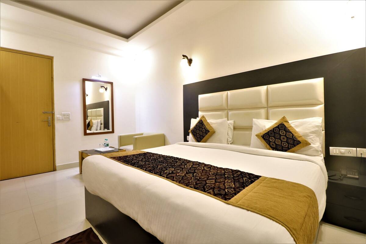 Une chambre d’hôtel moderne avec un grand lit, une table de chevet, un miroir et une petite table.