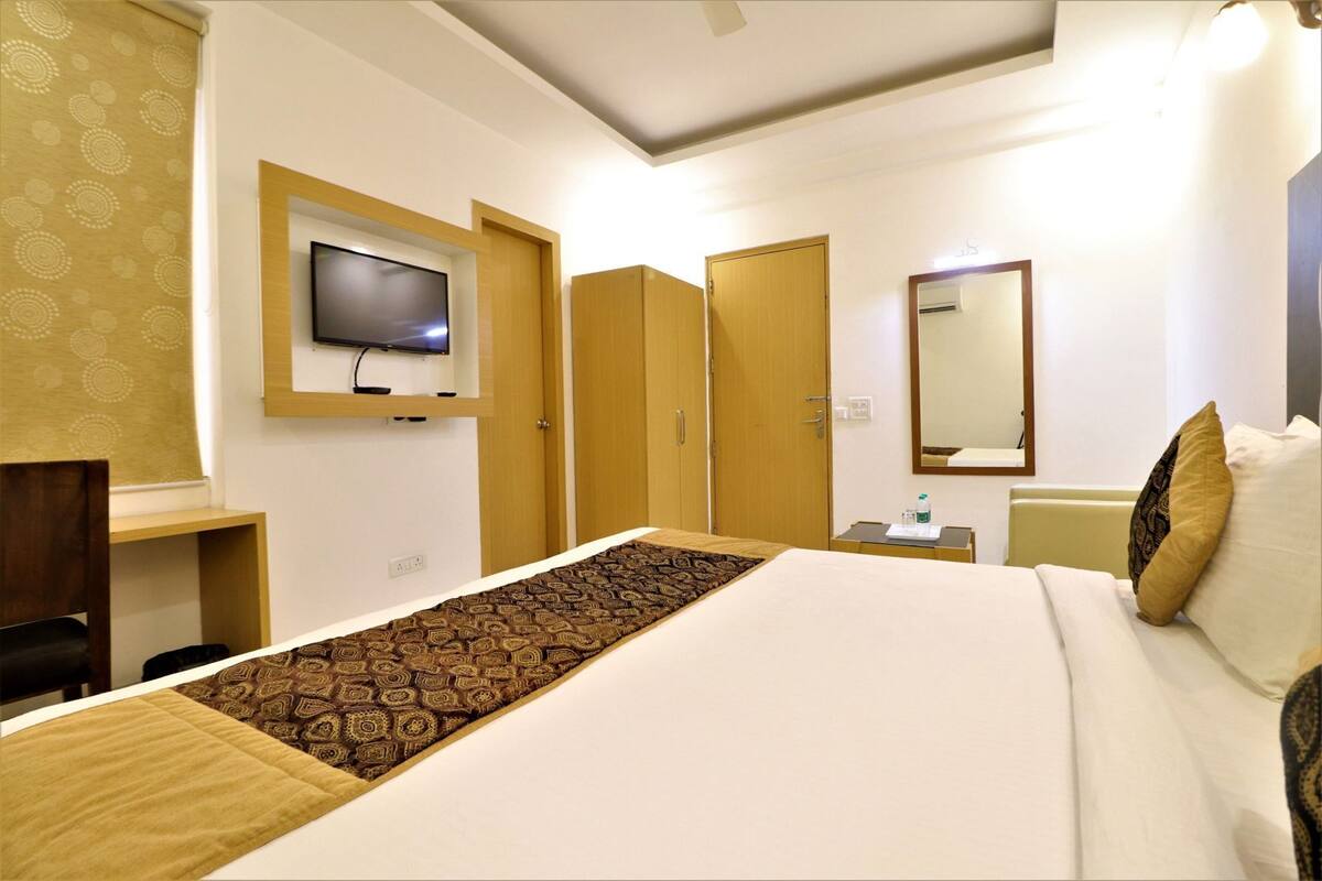 Une chambre d’hôtel équipée d’un lit, d’un téléviseur fixé au mur, d’un bureau et d’un miroir.