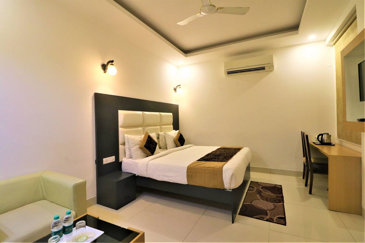 Une chambre d’hôtel moderne équipée d’un lit, d’un bureau, d’une chaise, d’un canapé et d’un ventilateur de plafond.
