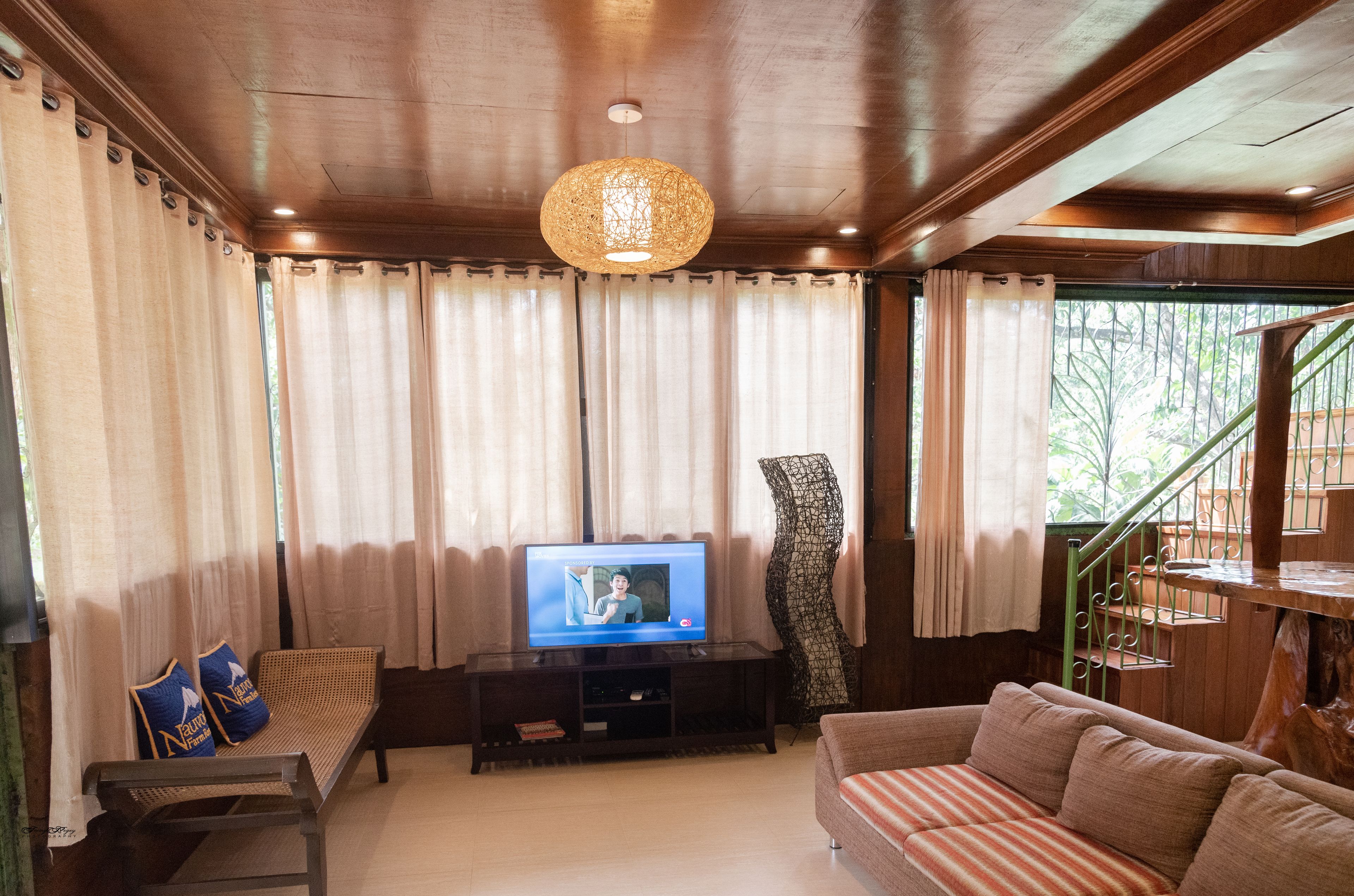 A living room with a television, a sofa, a bench, and a staircase.
