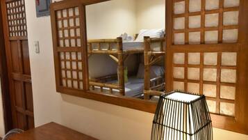 A room with a wooden bunk bed, a mirror with a wooden frame, and a black lamp on a wooden table.