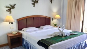 Une chambre d’hôtel comprenant un lit, deux lampes fixées au mur, un téléphone, des œuvres d’art décoratives accrochées au mur et une fenêtre avec des rideaux.
