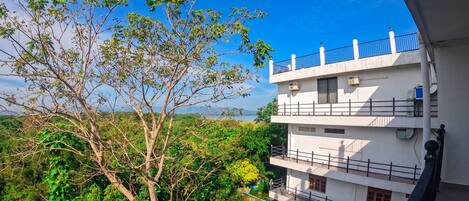 A multi-story building with balconies and a tree in the foreground.