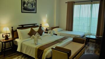 A hotel room with two beds, a checkered rug, a framed picture on the wall, and a window with curtains.