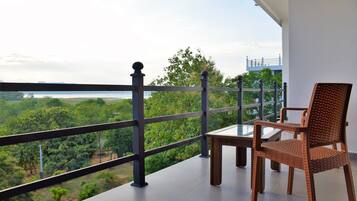 Een balkon met een tafel en stoelen, met uitzicht op een weelderig landschap.