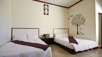 Ein Hotelzimmer mit zwei Betten, einem Nachttisch, einer Wanddekoration mit einem Baum und Vögeln sowie einem gerahmten Bild über dem Bett.