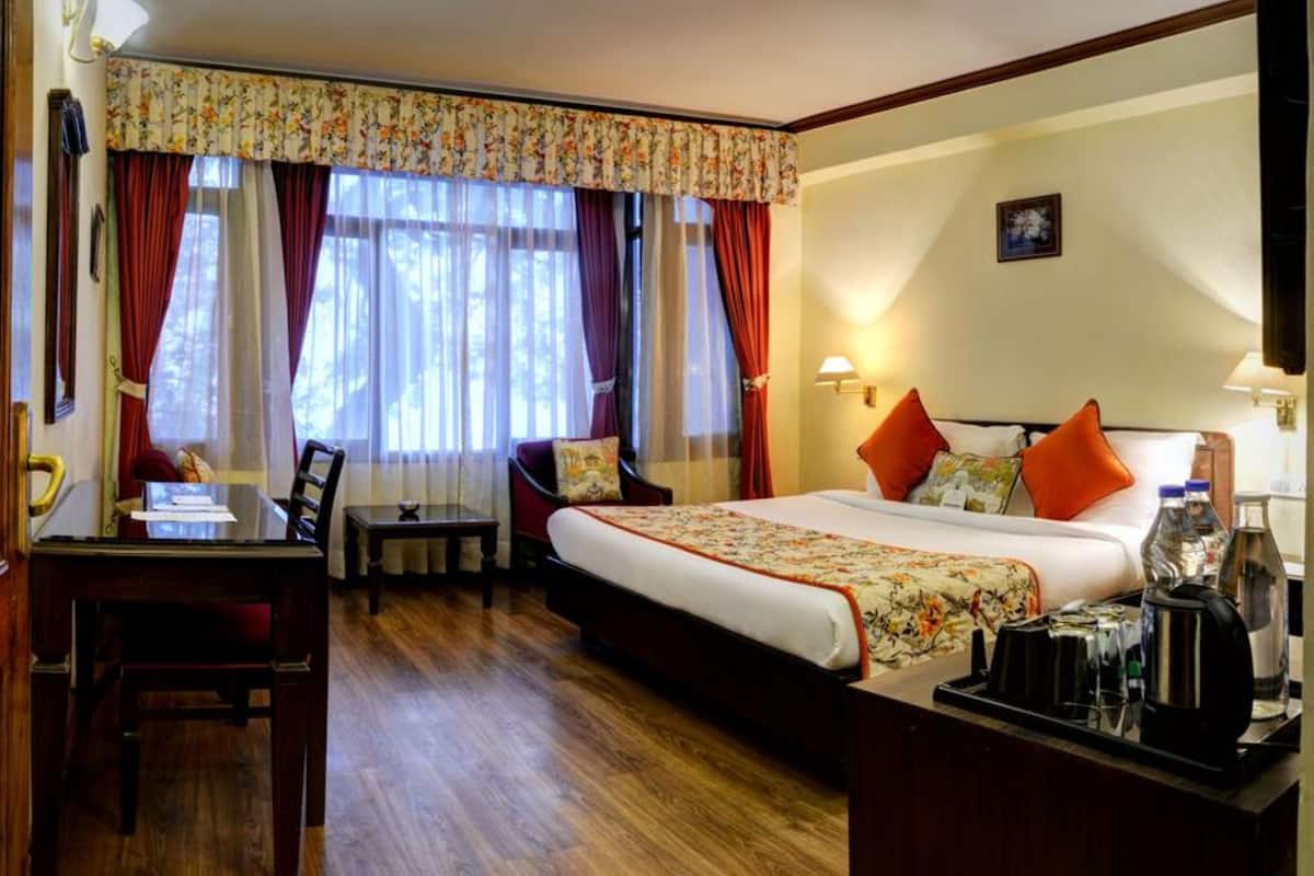 A hotel room with a large bed, a desk, a chair, and a TV.