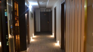 A hotel corridor with patterned carpet, doors on both sides, and a long hallway leading to a door at the end. - Altinpark Hotel (Kayseri)