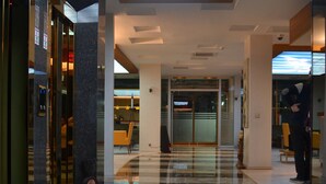 A modern lobby with a high ceiling and skylight, featuring a checkered floor pattern and glass doors leading to other areas. - Altinpark Hotel (Kayseri)