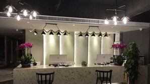 A reception area with two HP desktop computers, two chairs, and decorative lighting. - Manchen Hotel (Xi'an)